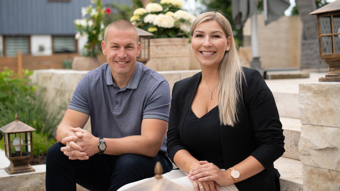 Jan Rohde, Immobilienmakler in Kassel und seine Frau Sabine Rohde, Immobilienmaklerin in Kassel auf einer Steintreppe im Garten eines Einfamilienhauses